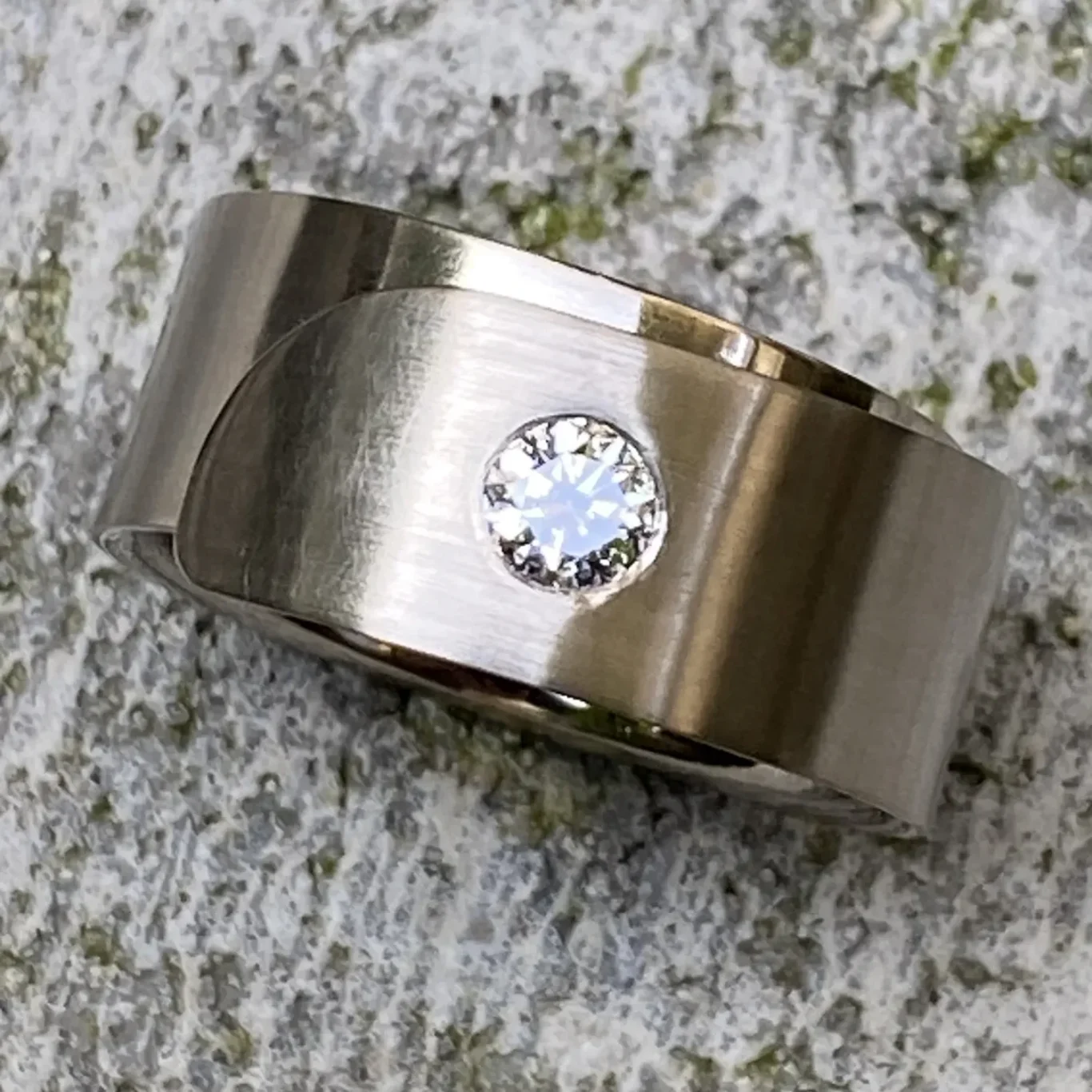 Schmaler, glänzender Ring aus Graugold mit einem funkelnden Brillanten.