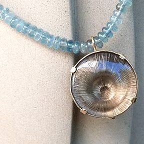 Kette mit blauen Steinen und einem runden, glänzenden Anhänger mit Rauchquarz.