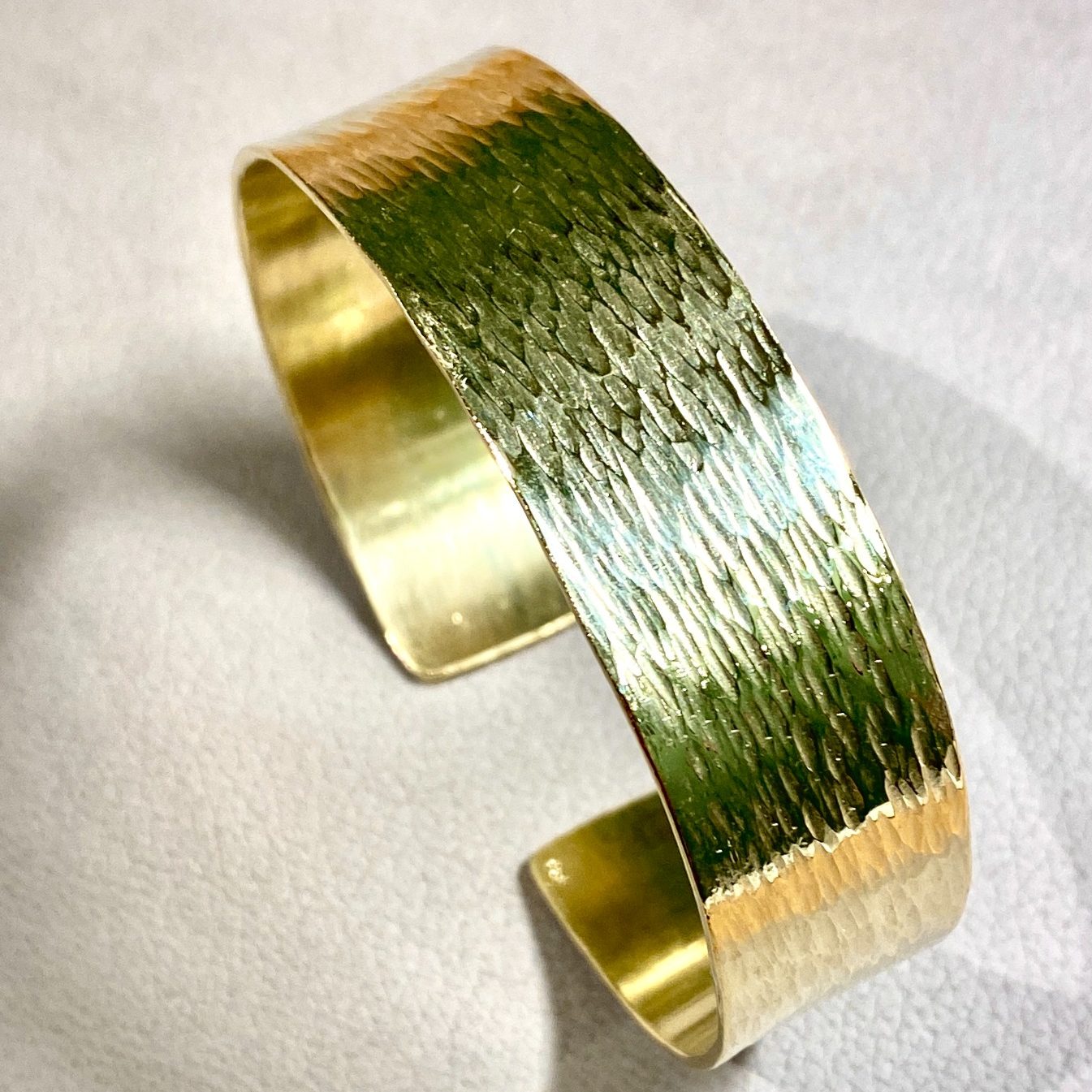 Goldfarbener Armreif mit strukturiertem, glänzendem Finish.
