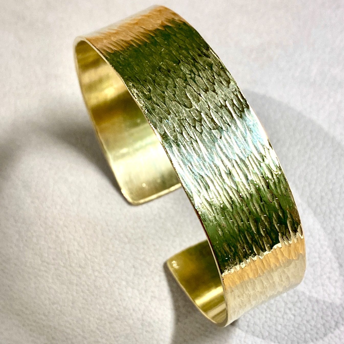 Breiter, goldener Armreif mit strukturiertem, glänzendem Finish.