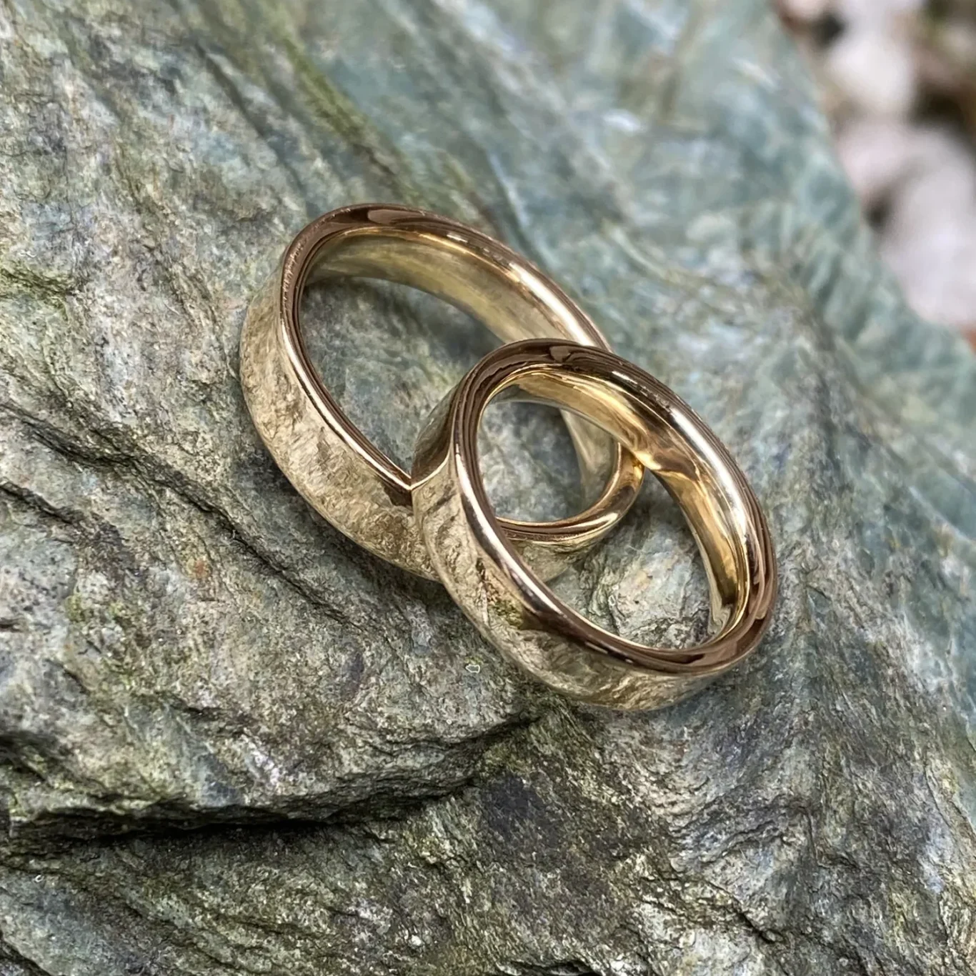 Zwei goldene Ringe liegen auf einem grauen Stein.