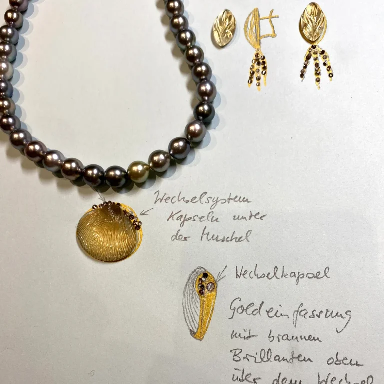 Perlenkette mit goldenem Anhänger und Ohrringen, handgefertigt, auf einem Notizblatt mit Designvorschlägen.
