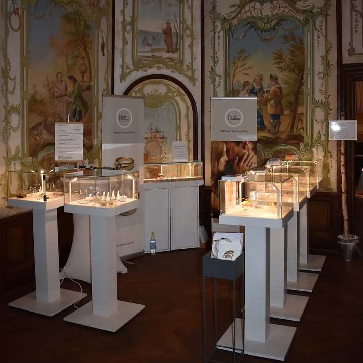 Ausstellung mit mehreren Beleuchtungsständen und Vitrinen in einem dekorativen Raum.