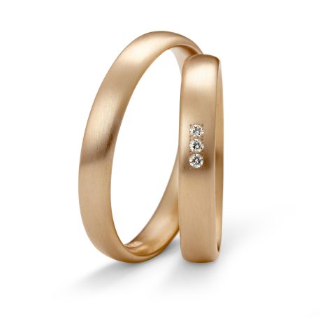 Zwei goldene Ringe mit drei kleinen Diamanten auf einer Seite.