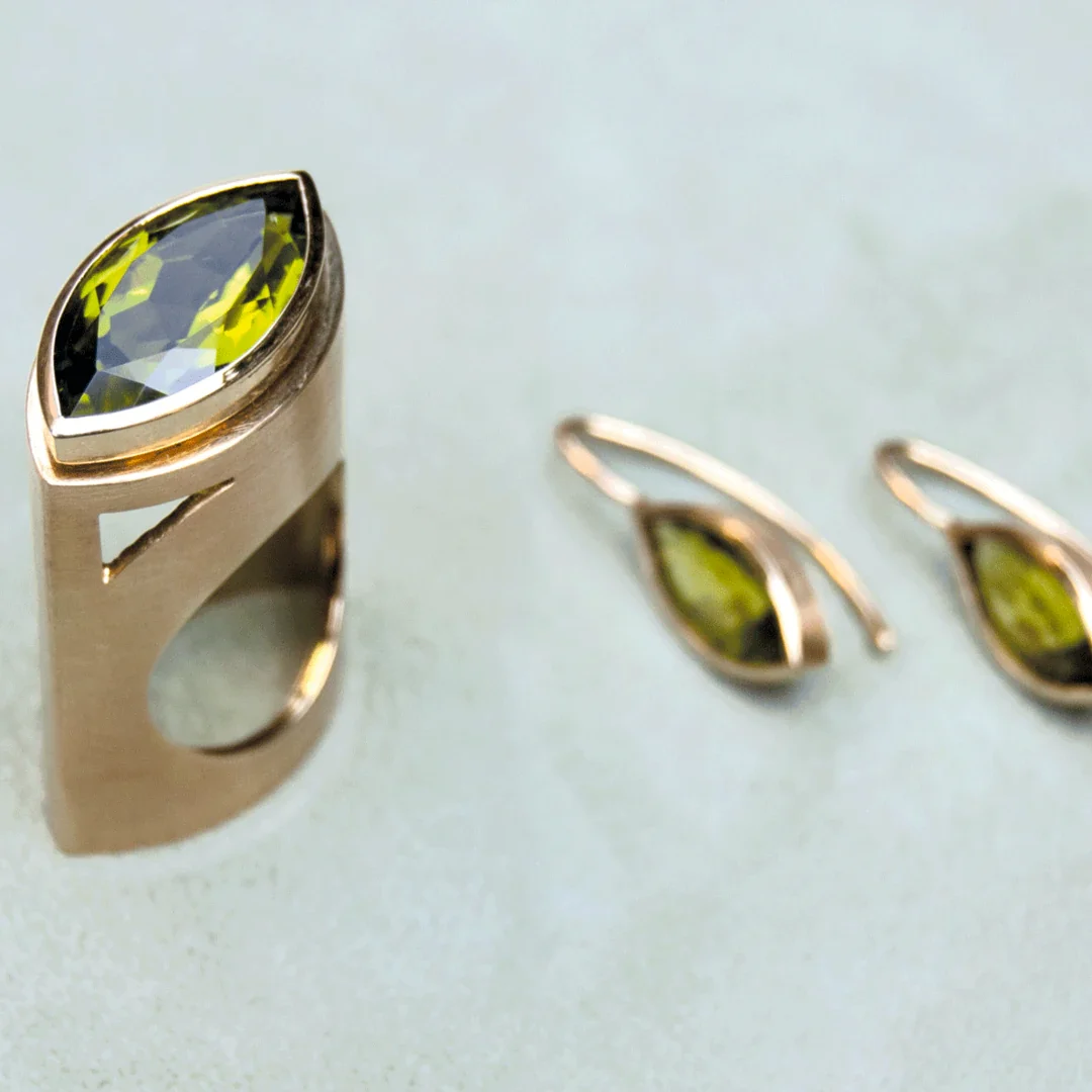 Goldring und Ohrringe mit grünen Steinen.