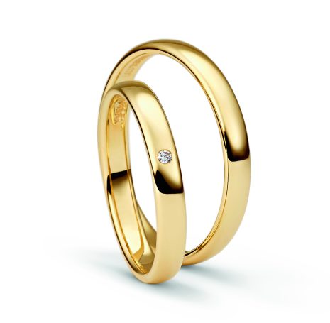 Zwei schlichte, goldene Ringe mit einem kleinen Diamanten.