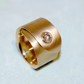 Gewickelter Goldring mit mattierter Oberfläche und einem zentralen, runden Brillanten.