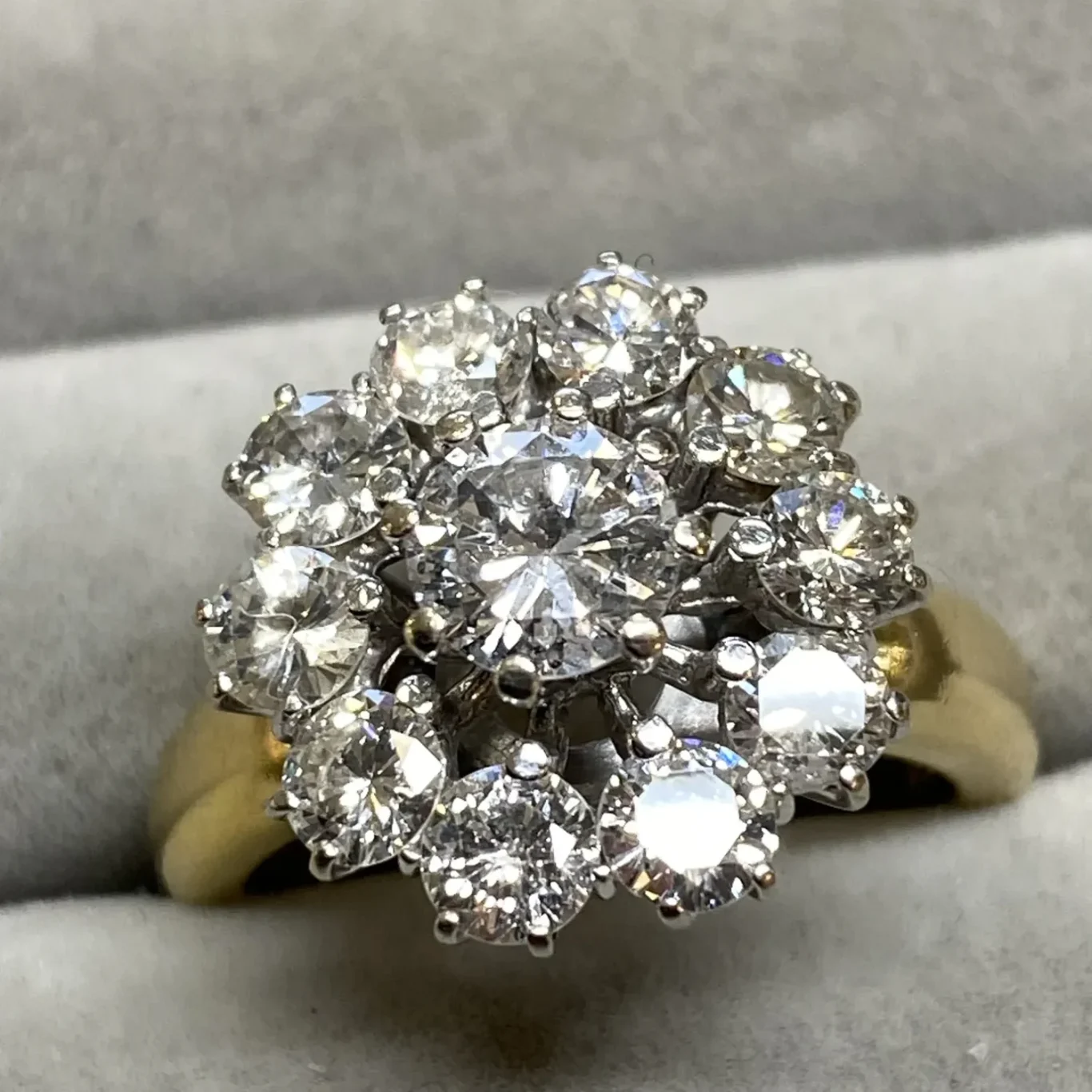 Ein goldener Ring mit funkelnden, blumig angeordneten Brillanten.