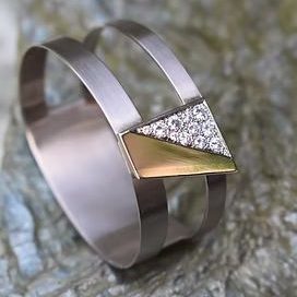 Eleganter Armreif aus Graugold mit einem Dreieck aus Gelbgold und glitzernden Brillanten.
