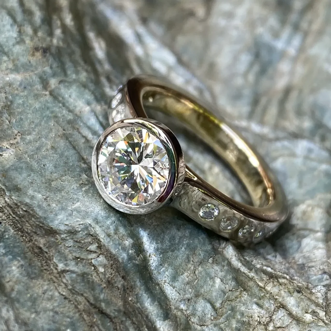 Ein goldener Ring mit einem großen mittigen und mehreren kleinen, seitlich in Reihe gefassten Brillanten.