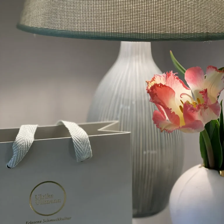 Eine Tischlampe, eine Blume in einer Vase und eine Geschenktüte.