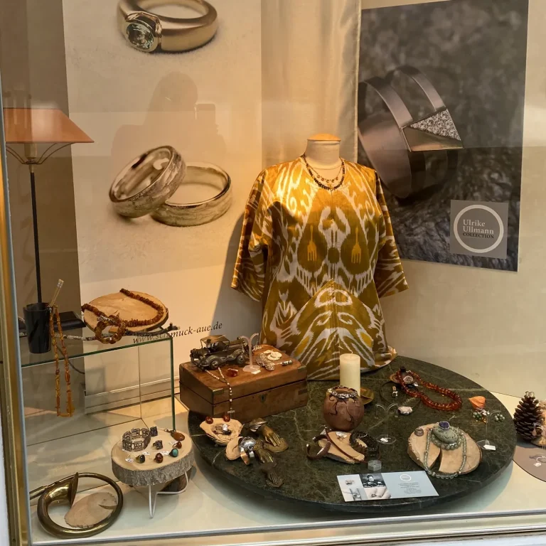 Schmuckauslage mit Ringen, Halsketten, Armbändern und einem dekorativen Kleid.